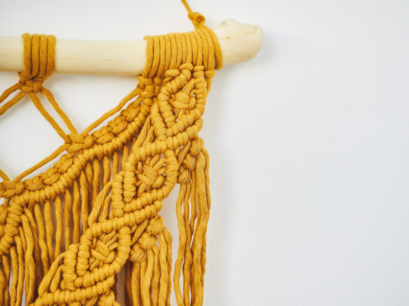 Yellow macrame hanging with wooden stick hanger